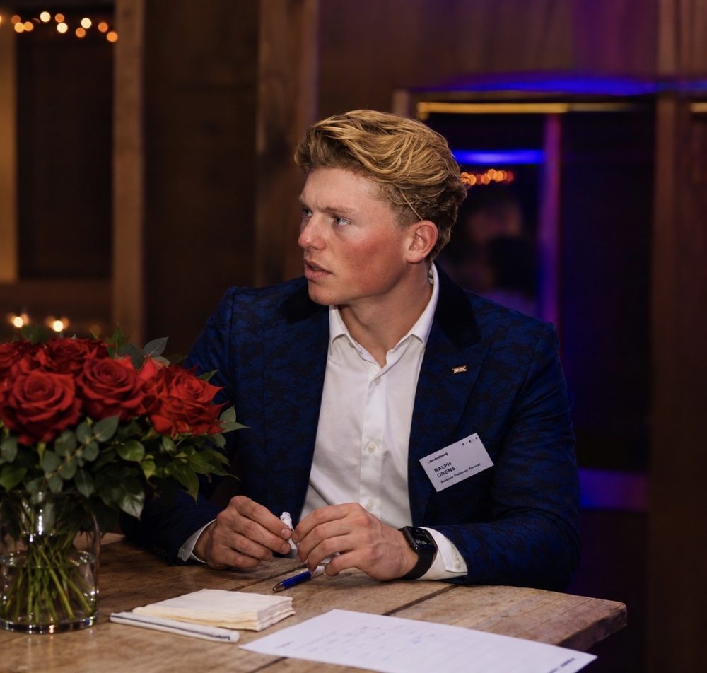 Ralph Orens aan een tafel met rode rozen, kijkend naar rechts